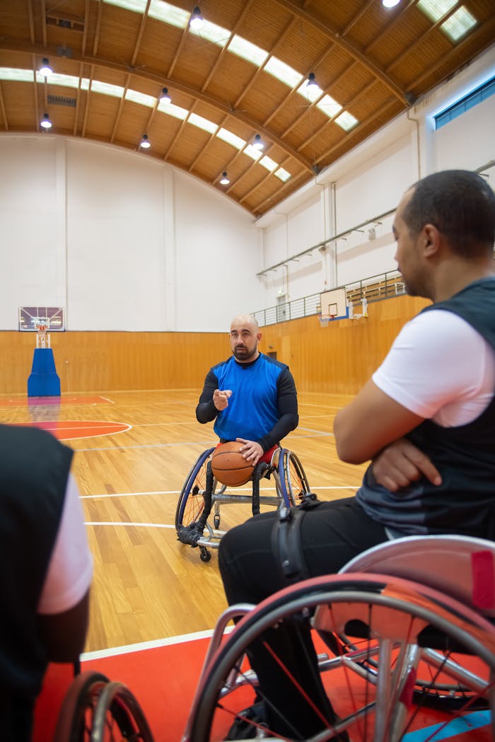 hero-img-01 Coach instructing players in an indoor wheelchair basketball court.